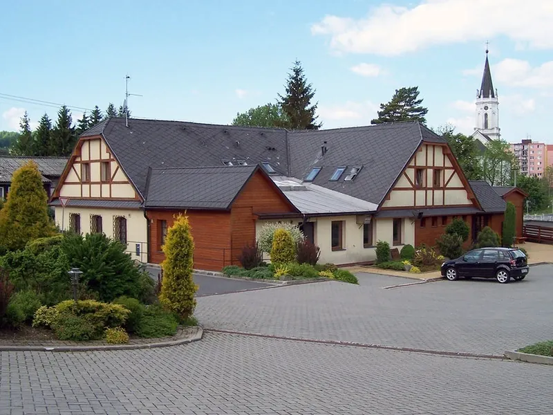 Budovy penzionu s parkovištěm před domem
