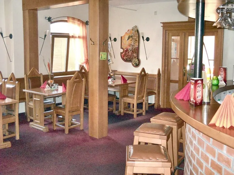 Restaurace s dřevěnými židlemi, sloupy a zděným barem